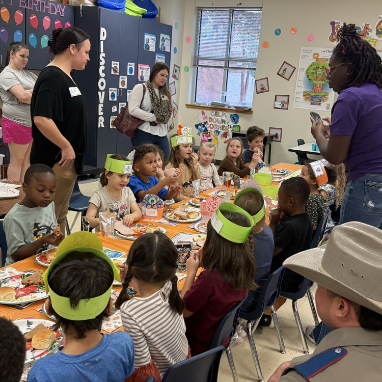 kindergarten students partaking in a Thanksgiving feast at a long table