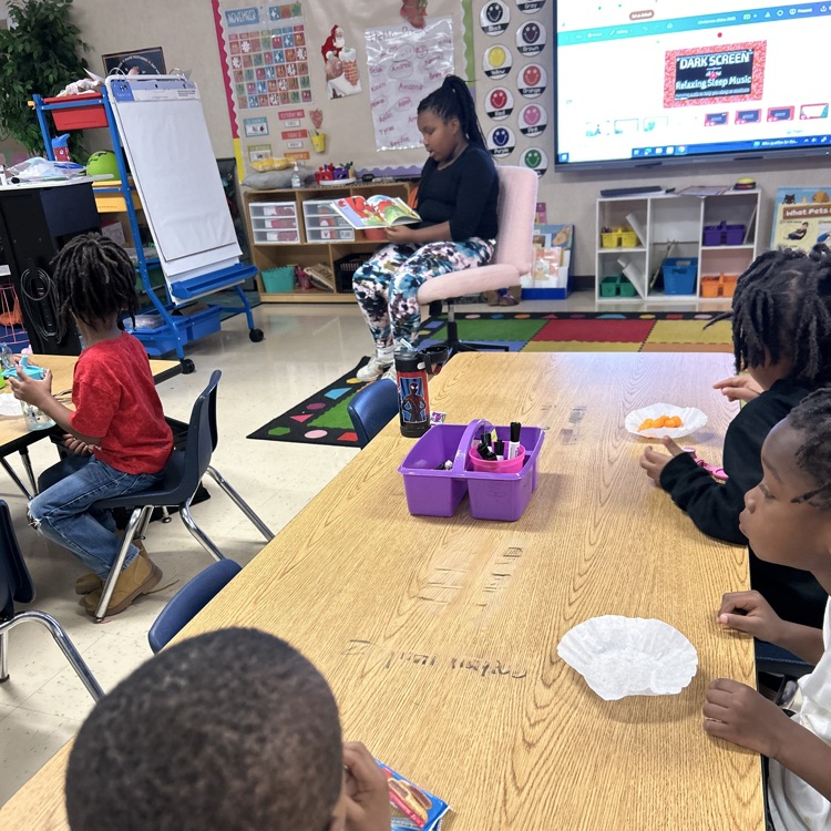 fourth grade student reading to pre-K students during snack time