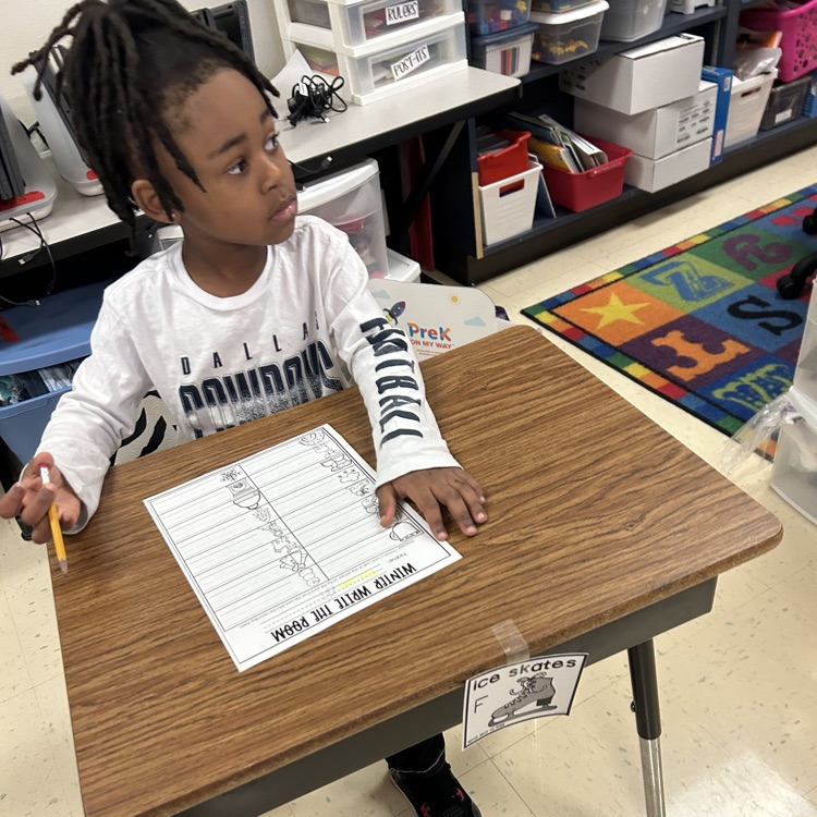 Pre-K student writing winter words at their desk