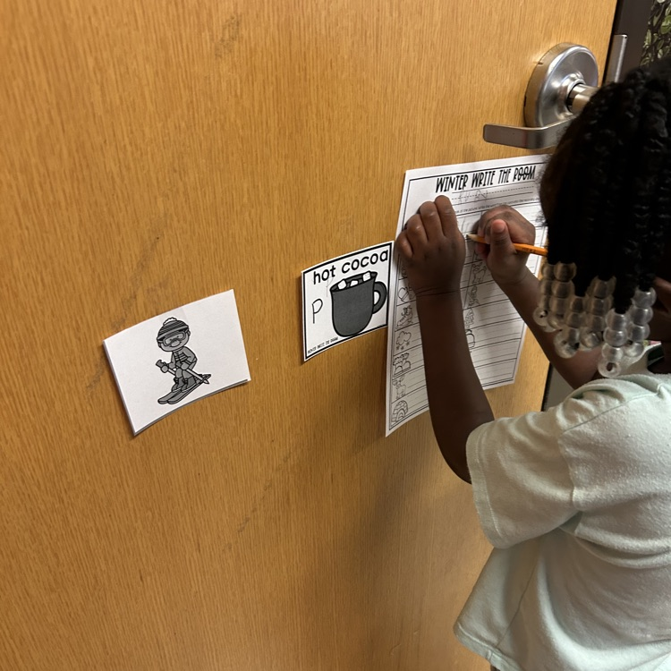 pre-K student writing winter words around the room