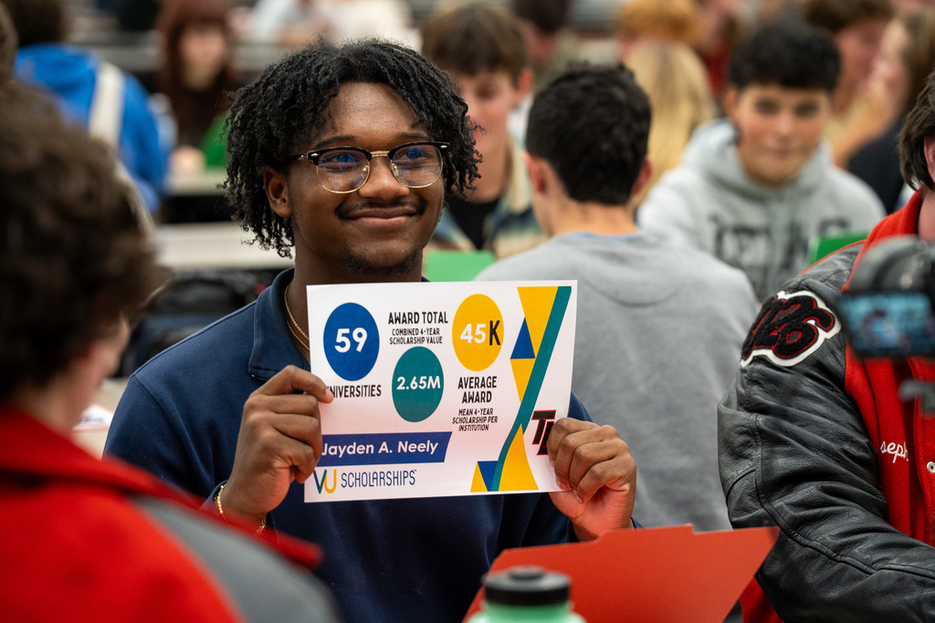 Tyler Legacy Student smiles while holding UV Scholarships certificate.