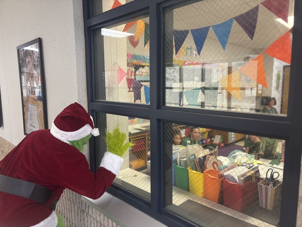 Grinch waiving at students through a window.