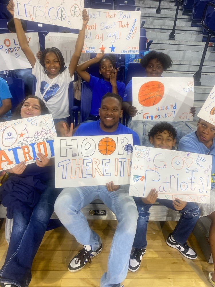 students and teacher smiling holding sign