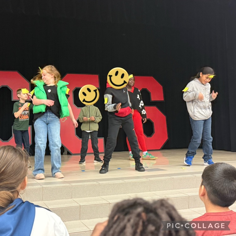 Student standing on the stage, shaking off their sticky note