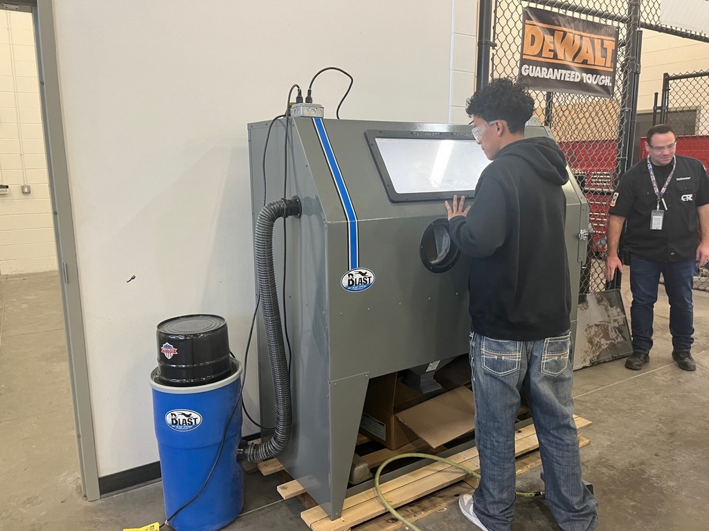 A Tyler ISD CTC student using the dry media blast cabinet in the shop.