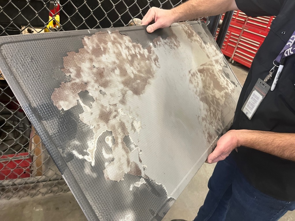 A Tyler ISD CTC Automotive teacher showing the result of dry blasting. The light grey is the result of the blasted area.