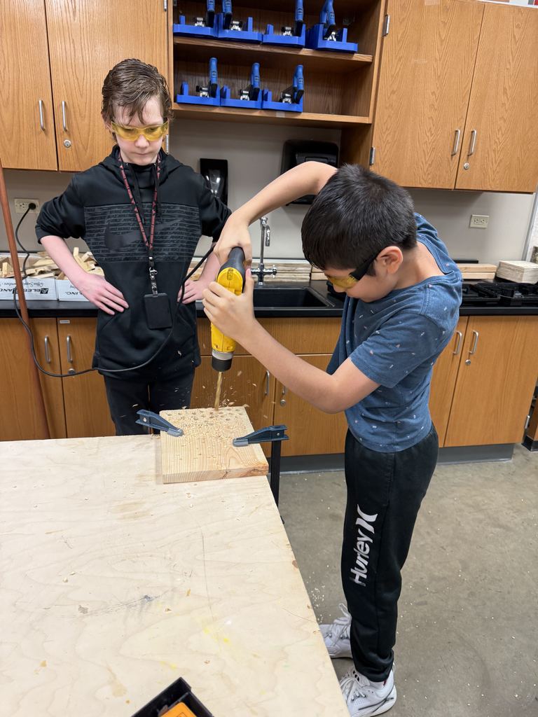 A boy is drilling a hole into wood.