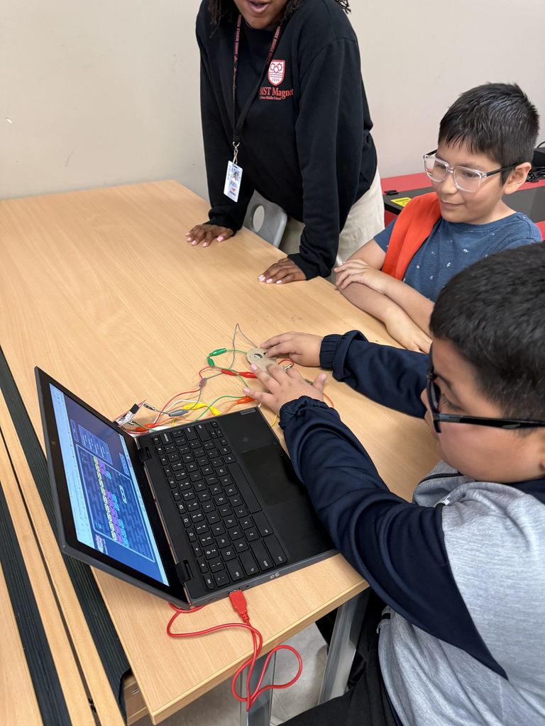 Two boys are using a circuit board and a computer.