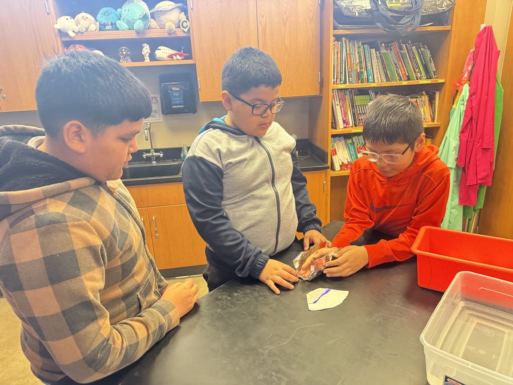 Three boys are conducting an experiment with aluminum foil.