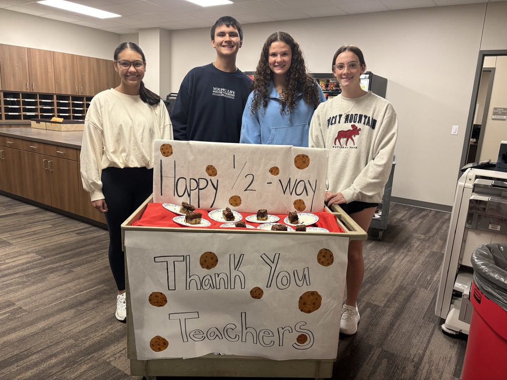 Tyler Legacy junior student council representatives with a cart full of brookies and a sign that says "Happy 1/2 way Thank you teachers" with cookies on it