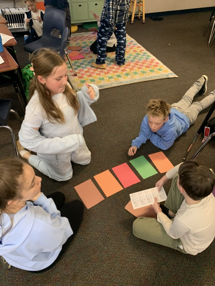 students sitting on the floor completing an activity with construction paper