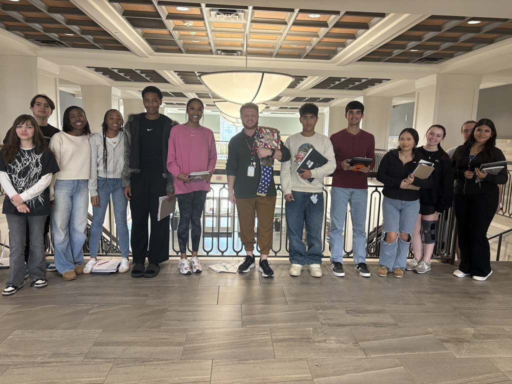 Tyler Legacy Walk Through Wednesday Champion of the week, Mr. Smith in the front lobby with the champion belt and his students around him
