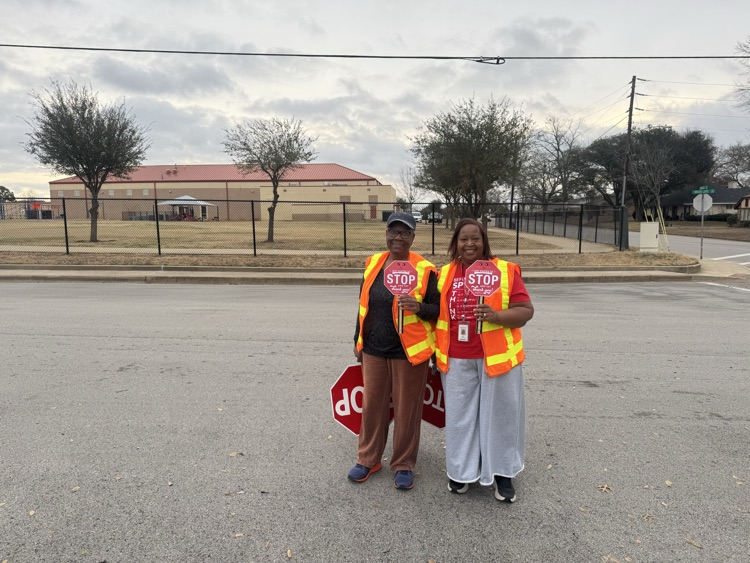 crossing guards holding stop signs in front of the school