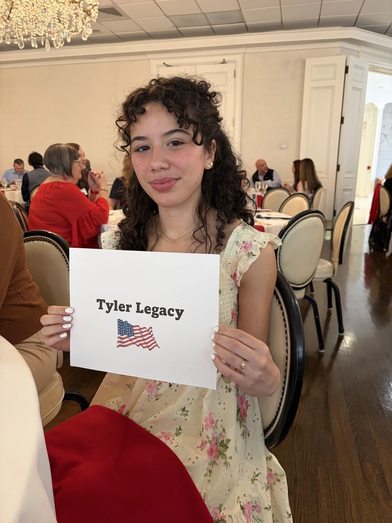 Tyler Legacy senior, Mya Flack holding up a "Tyler Legacy" sign at the DAR tea