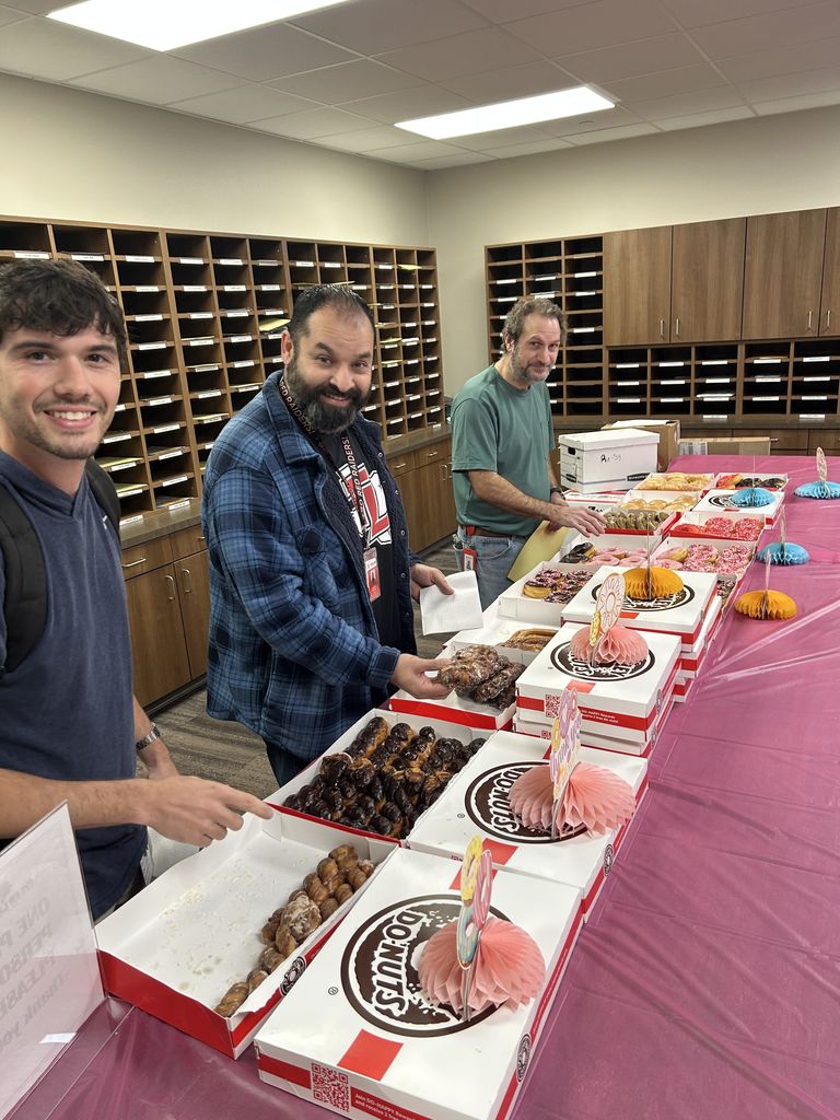 Tyler Legacy teachers posing behind a table full of donuts