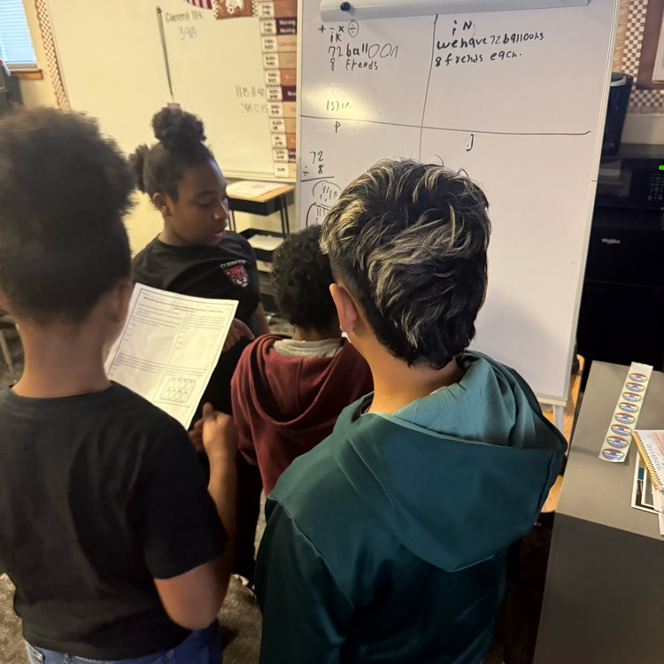 student s showing their math work on a vertical board