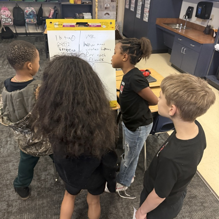 student s showing their math work on a vertical board