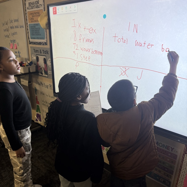 student s showing their math work on a vertical board