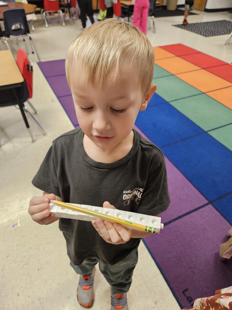 Kindergarten students using blocks to measure classroom items.