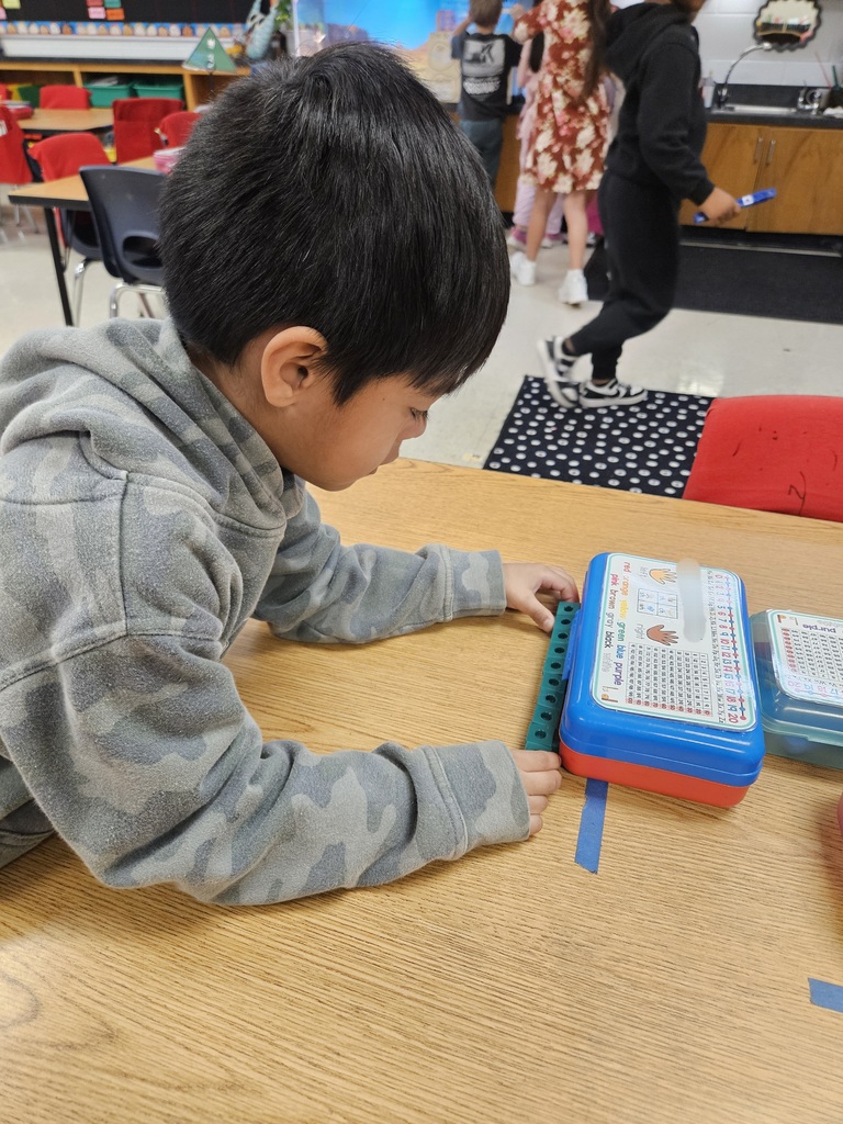 Kindergarten students using blocks to measure classroom items.