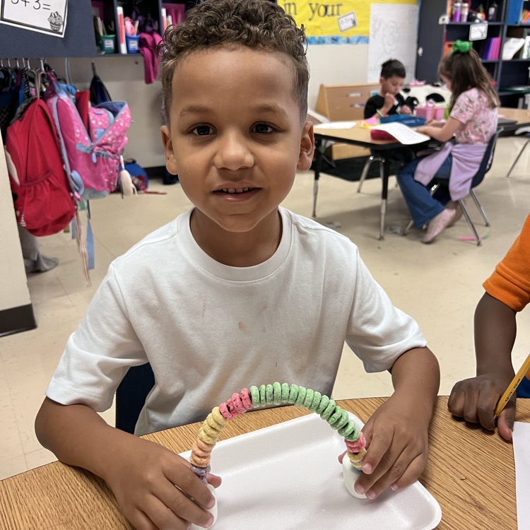 student displaying their rainbow craft