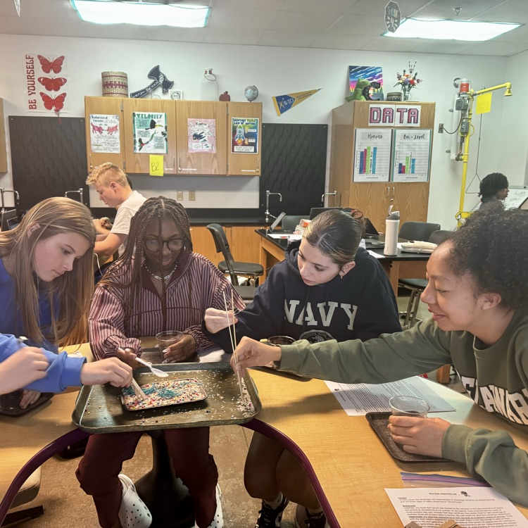 students engaged in a lab simulation at the teacher table 