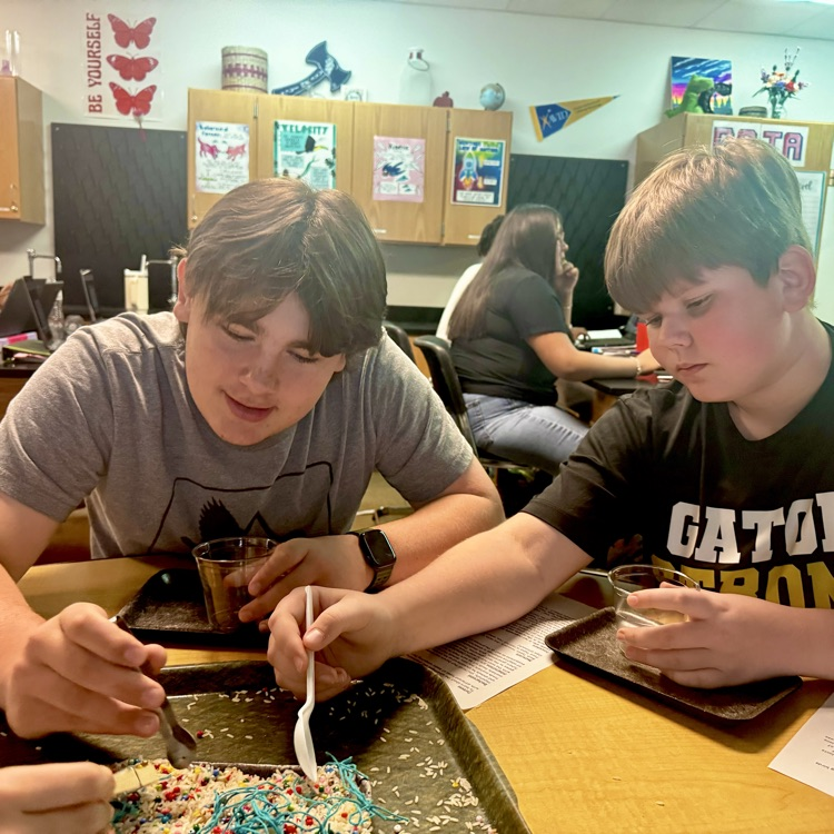 students engaged in a lab simulation at the teacher table 