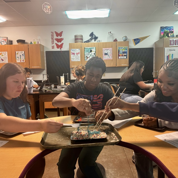 students engaged in a lab simulation at the teacher table 