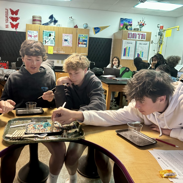 students engaged in a lab simulation at the teacher table 