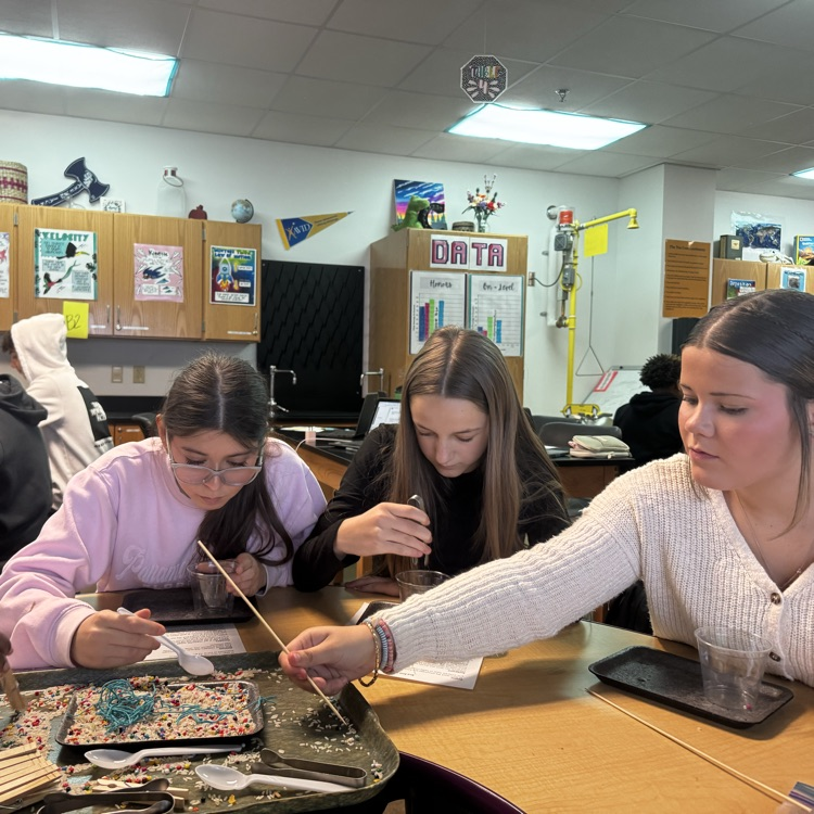 students engaged in a lab simulation at the teacher table 