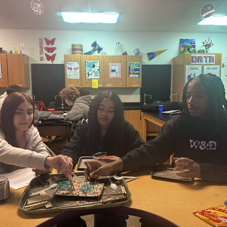 students engaged in a lab simulation at the teacher table 