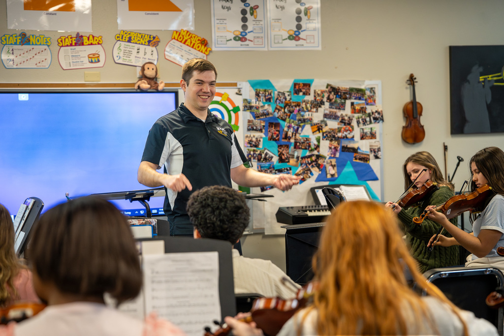 Caldwell Music Teacher smiles while instructing students to play in class.
