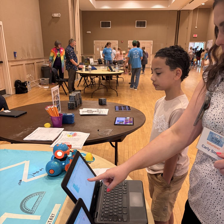 Students and teacher coding a robot with a laptop