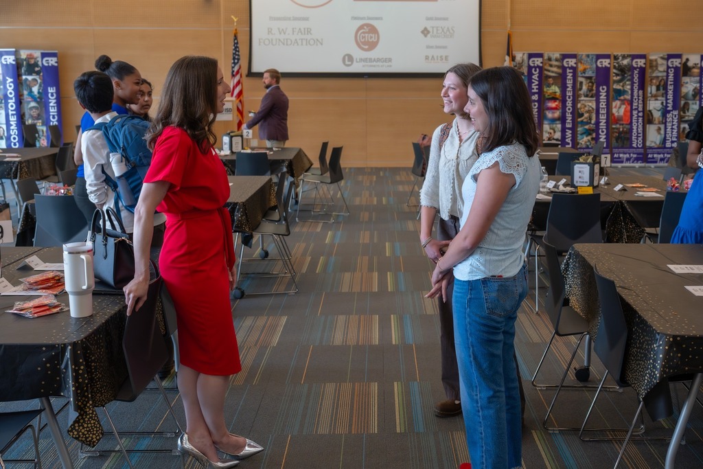 Students from Future Leaders of Tyler smile and chat with a presenter. 
