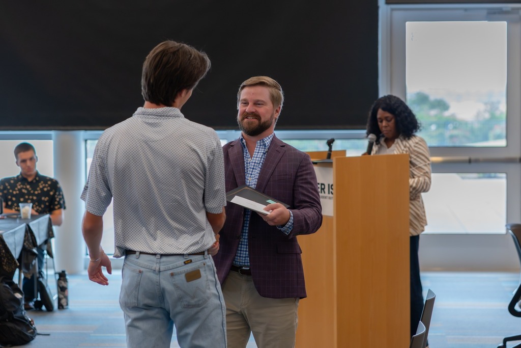 Man smiles and awards a student with his Future Leaders of Tyler graduation certificate.