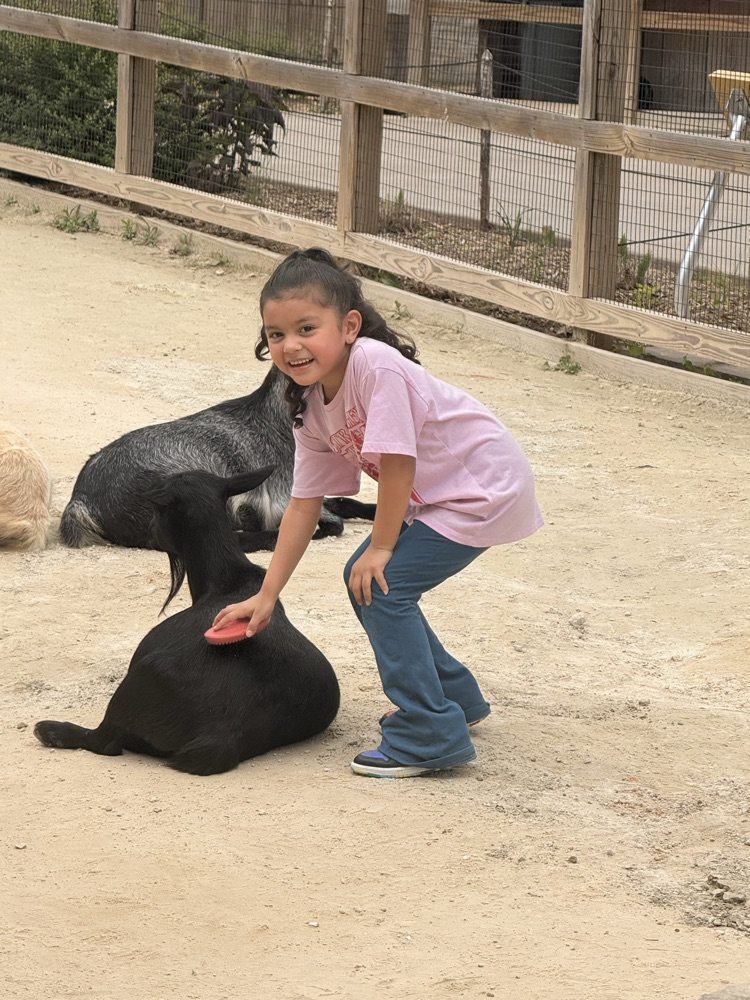 student petting goat and smiling