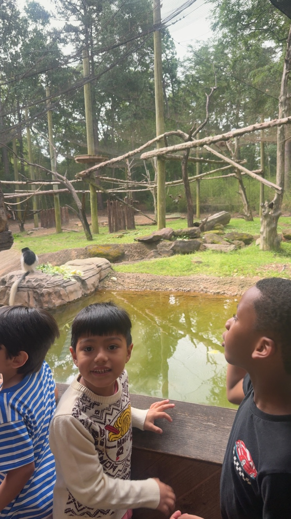 students smiling with zoo animals behind him