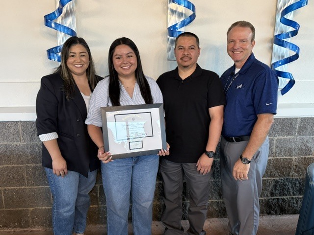 student and parents posing with plaque