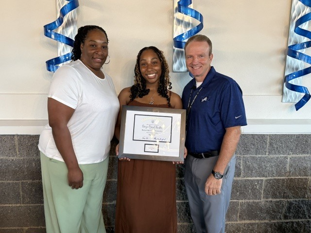 student and parents posing with plaque