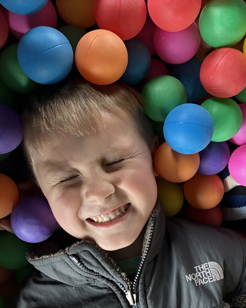 Student smiling in a ball pit. 