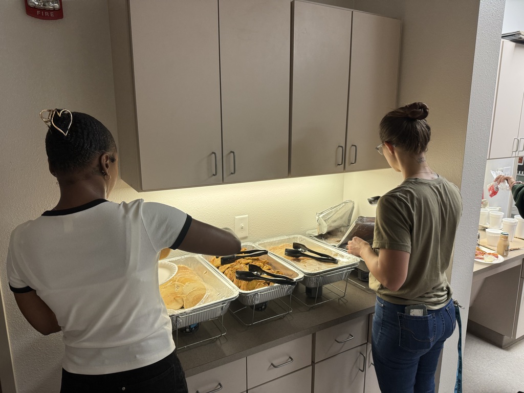 Teachers serving themselves pancakes, french toast, bacon and sausage.