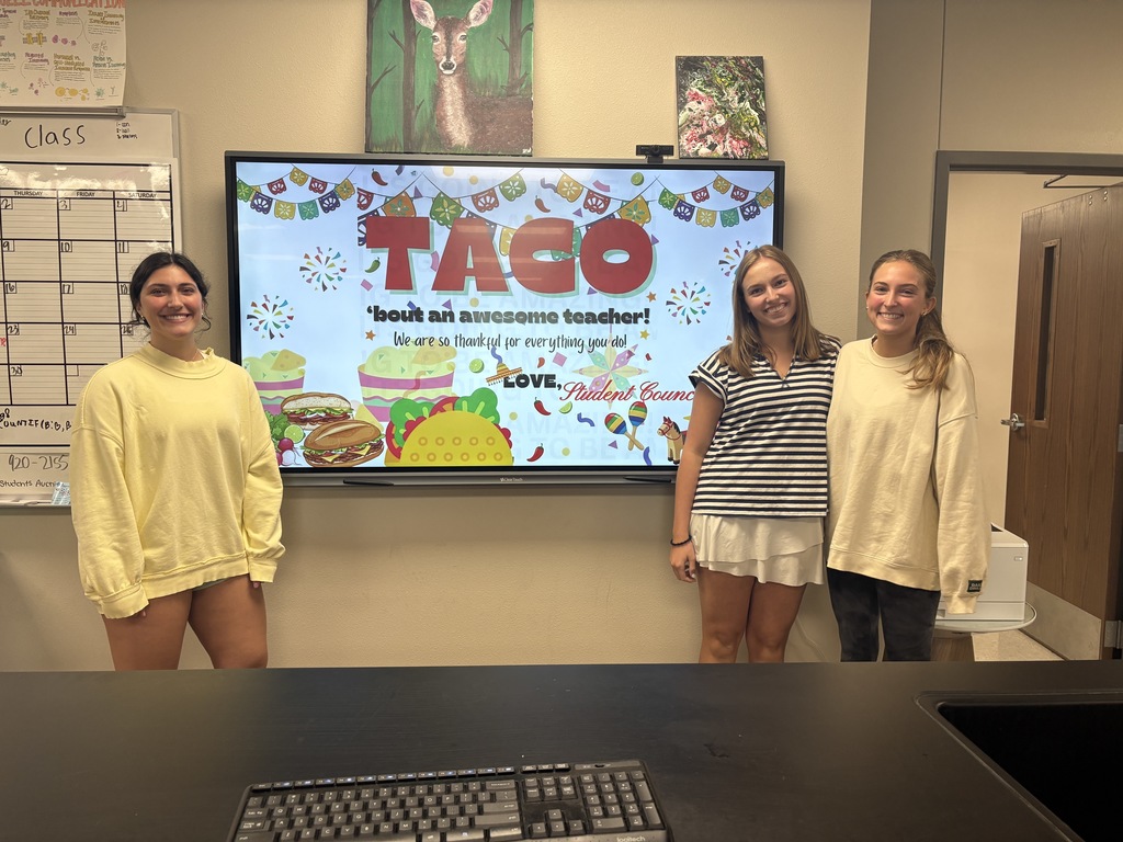 Student Council members with signs saying "Taco 'bout an awesome teacher"
