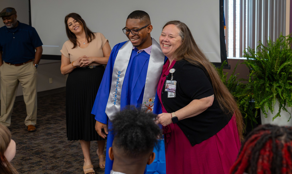 Project SEARCH Graduate smiles with teacher.