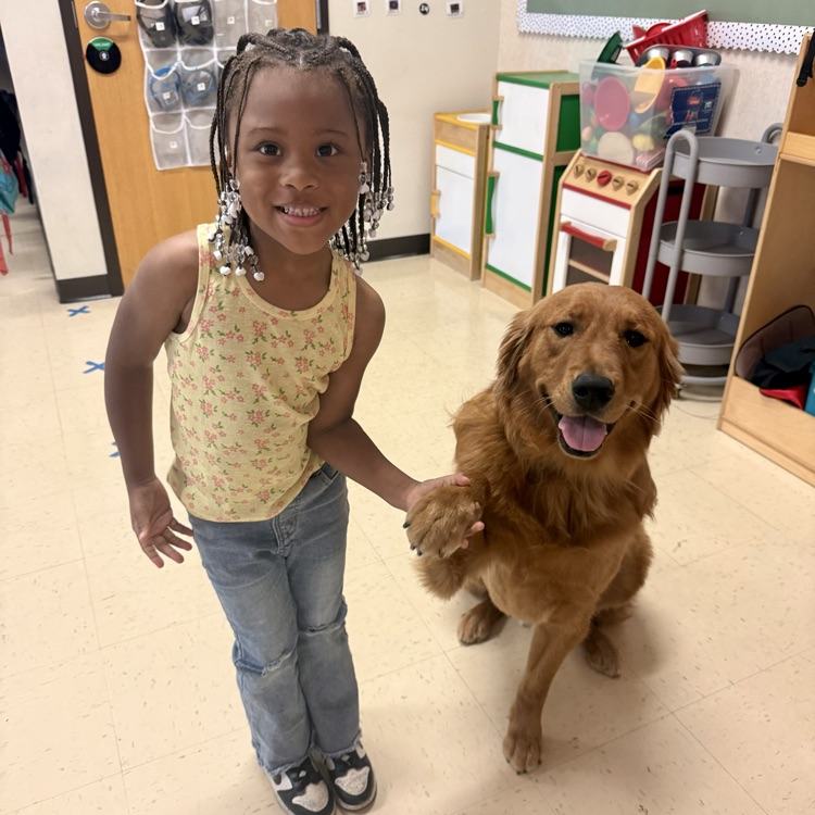 student sitting with golden retriever