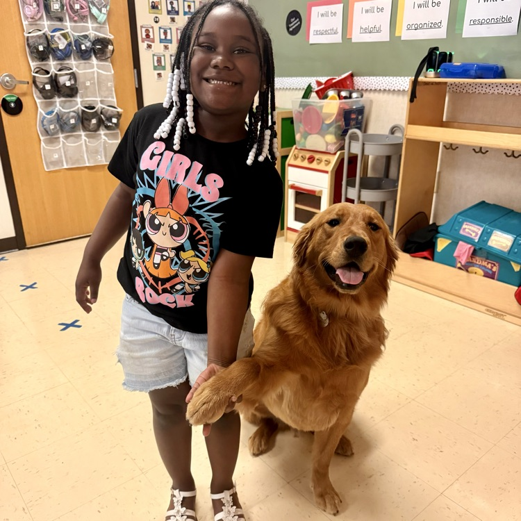 student sitting with golden retriever