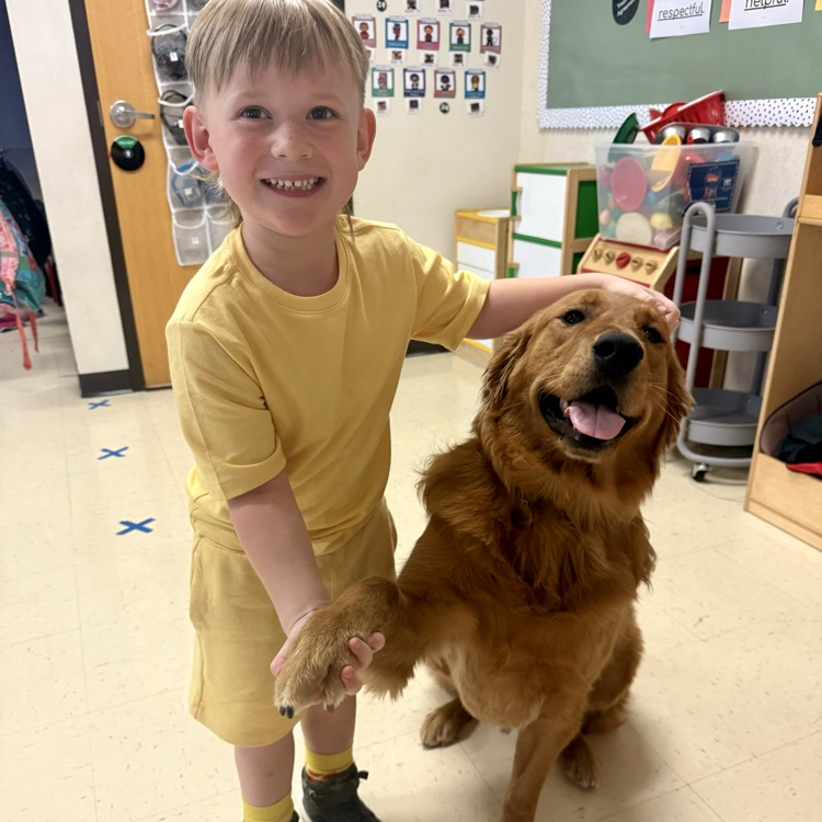 student sitting with golden retriever