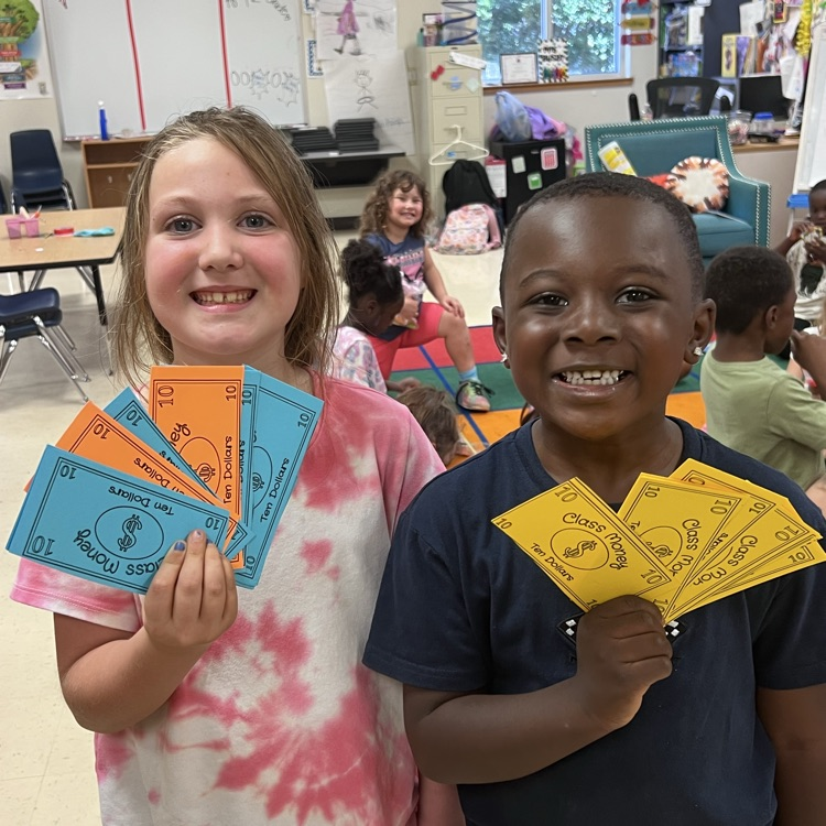 Students holding paper money they earned