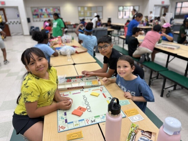three kids smiling playing monopoly