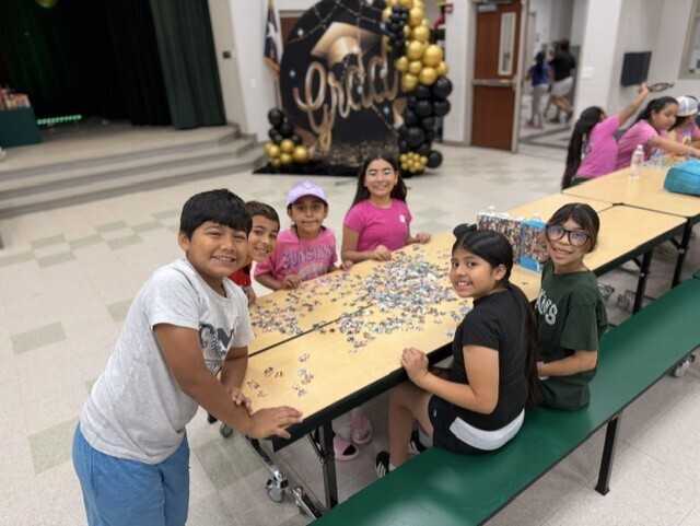 six kids smiling putting together a puzzle