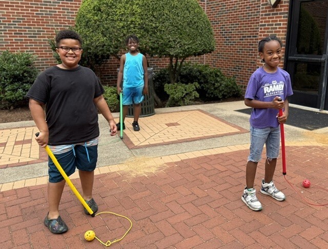 three boys smiling holding batons
